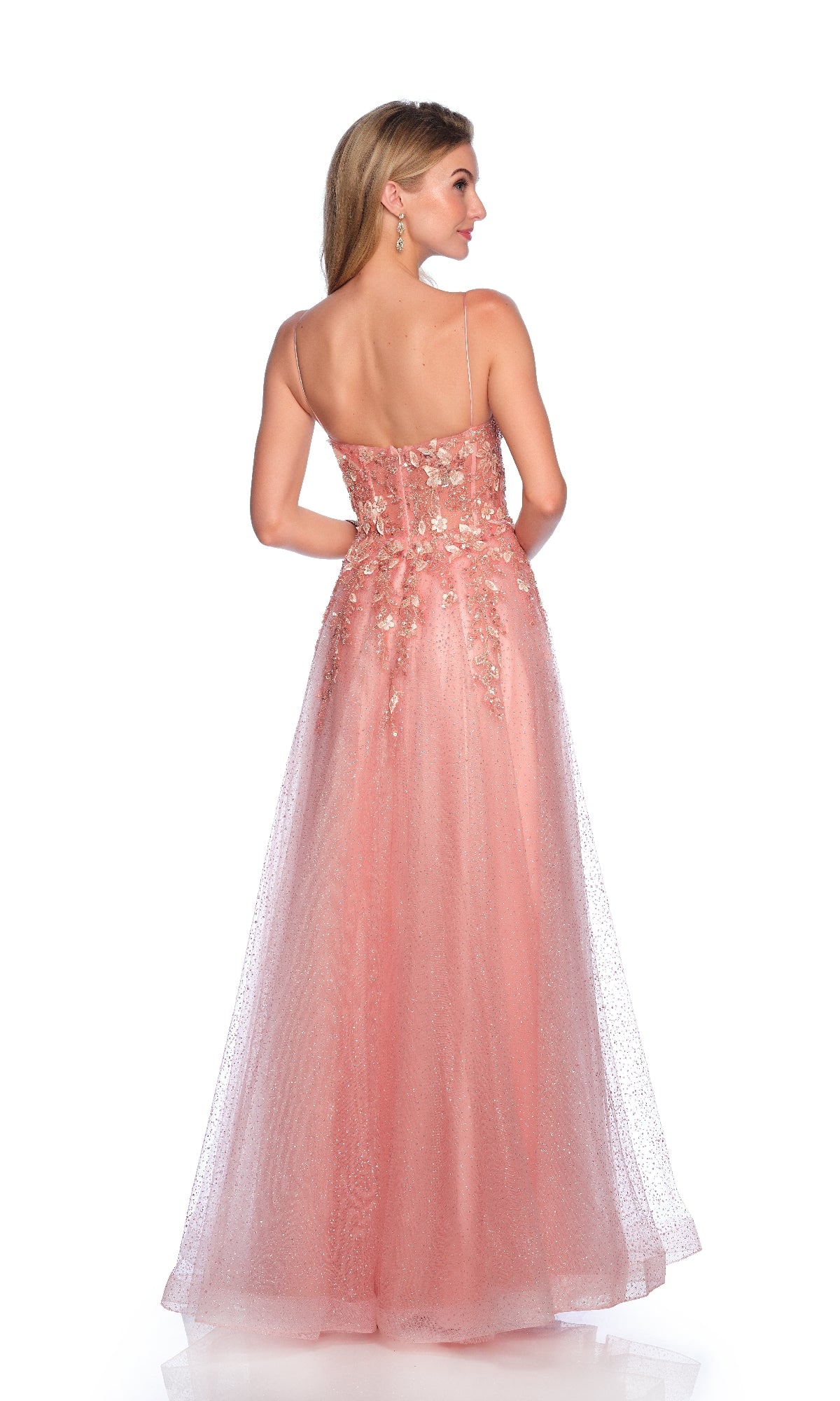 A woman wears the Dusty Rose Pink Prom Dress (Dave & Johnny 12162) with 3D floral appliques, a sheer sparkly overlay, tulle A-line skirt, and open back as she stands facing away.